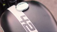 Close-up of a matte black motorcycle fuel tank with a white stripe and a silver fuel cap.