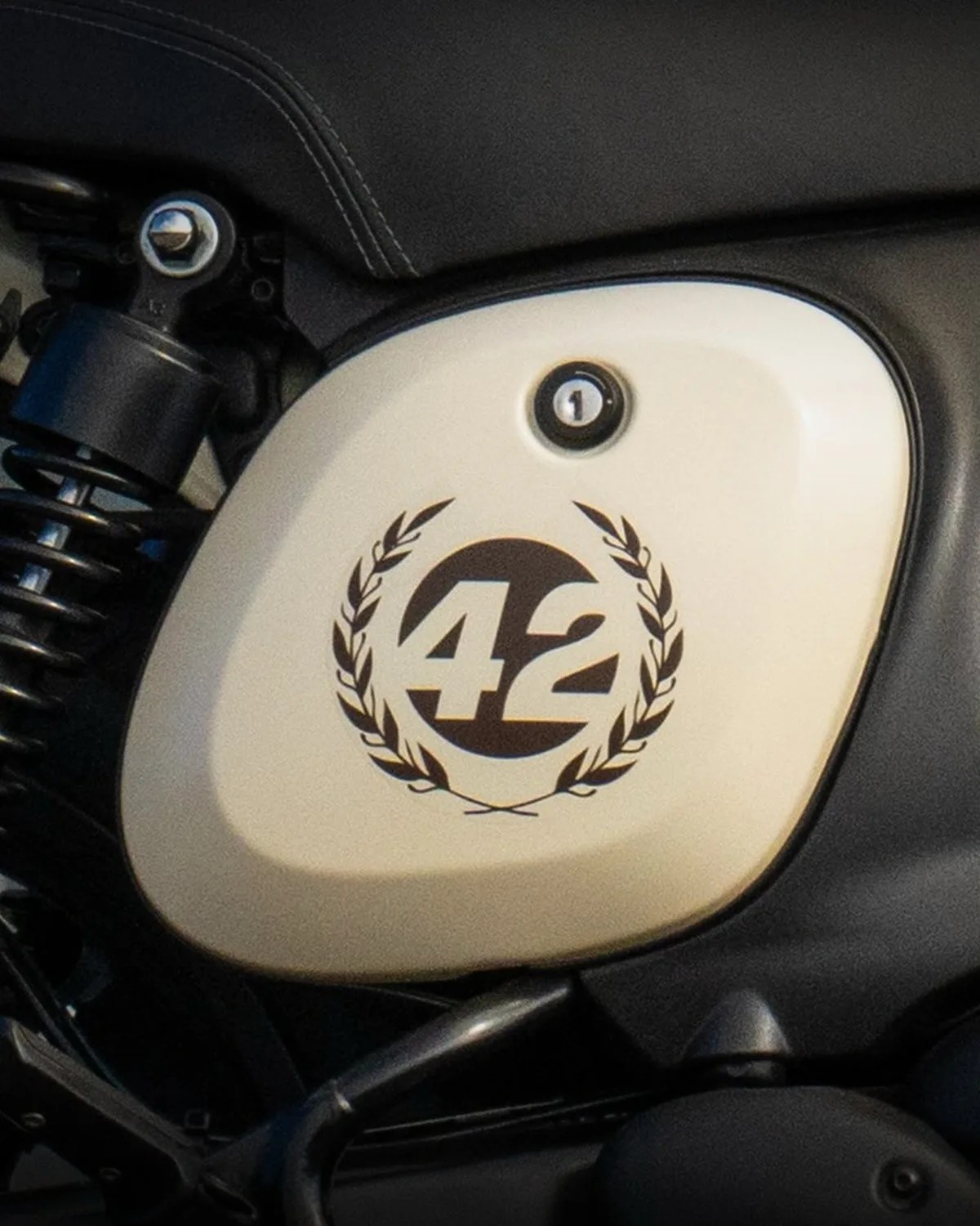 Cream-colored motorcycle side panel with black "42" logo surrounded by laurel wreath design.