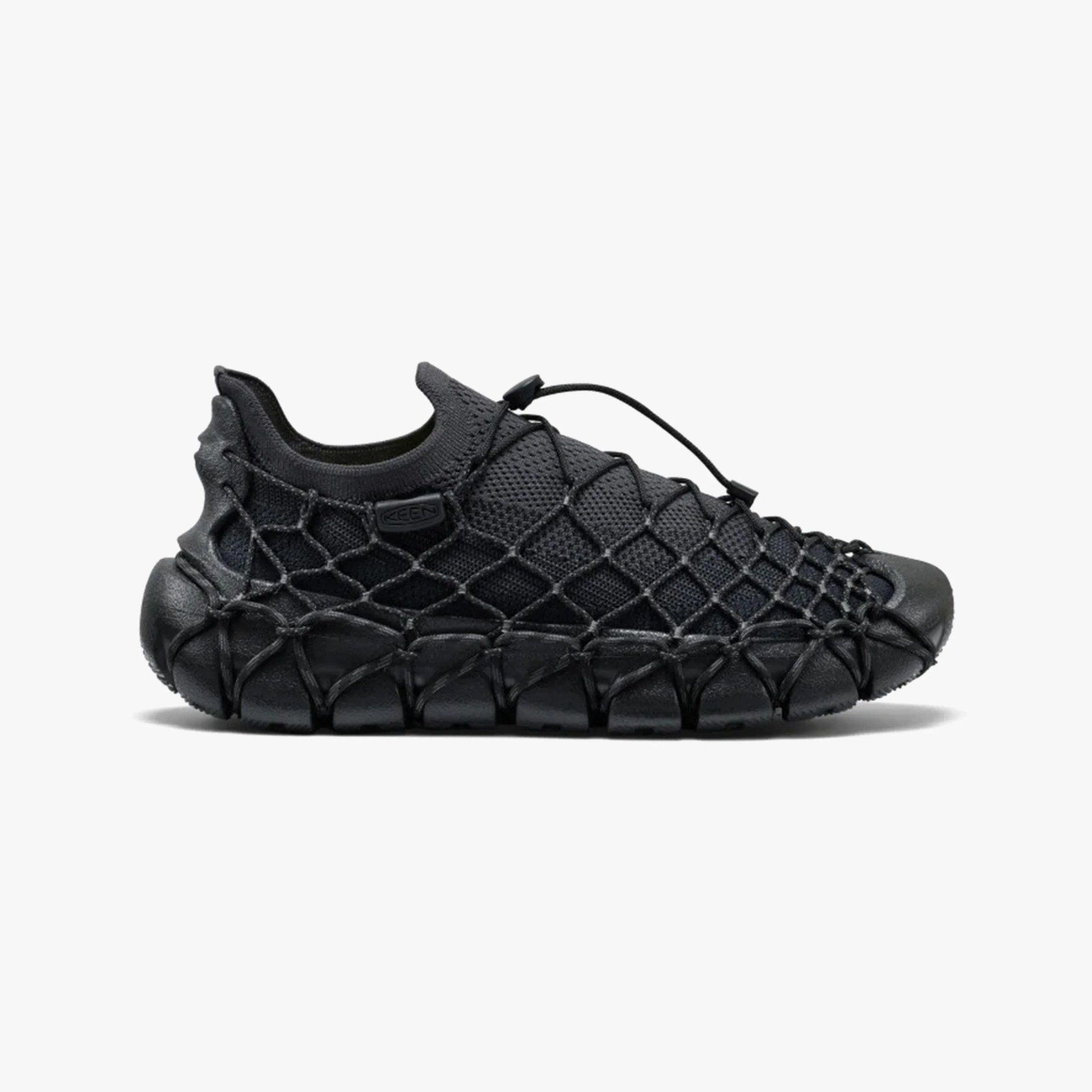 Black slip-on sneaker with mesh upper and netted cord overlay on sole and sides.