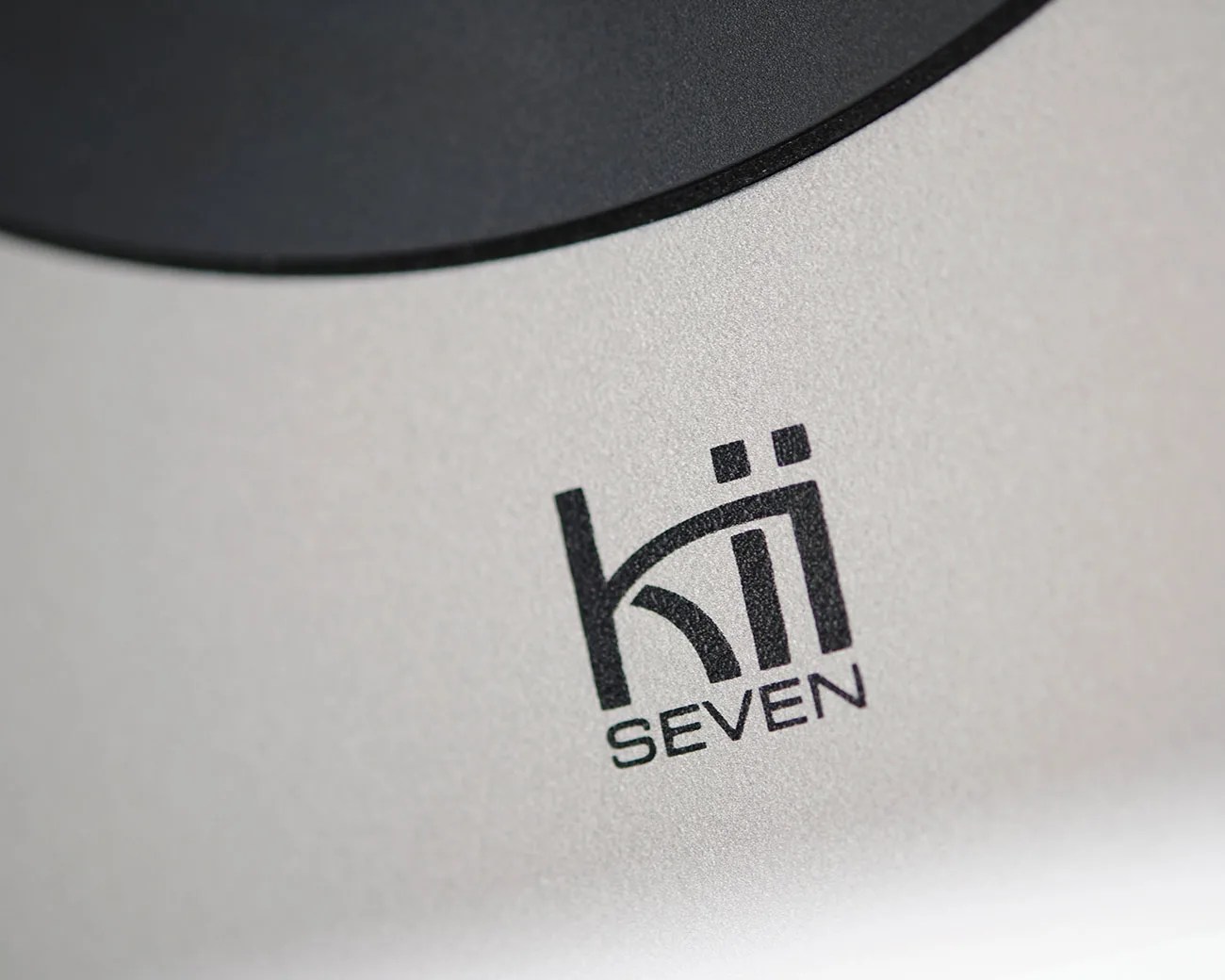 Close-up of a silver surface with a black "kii SEVEN" logo printed on it.