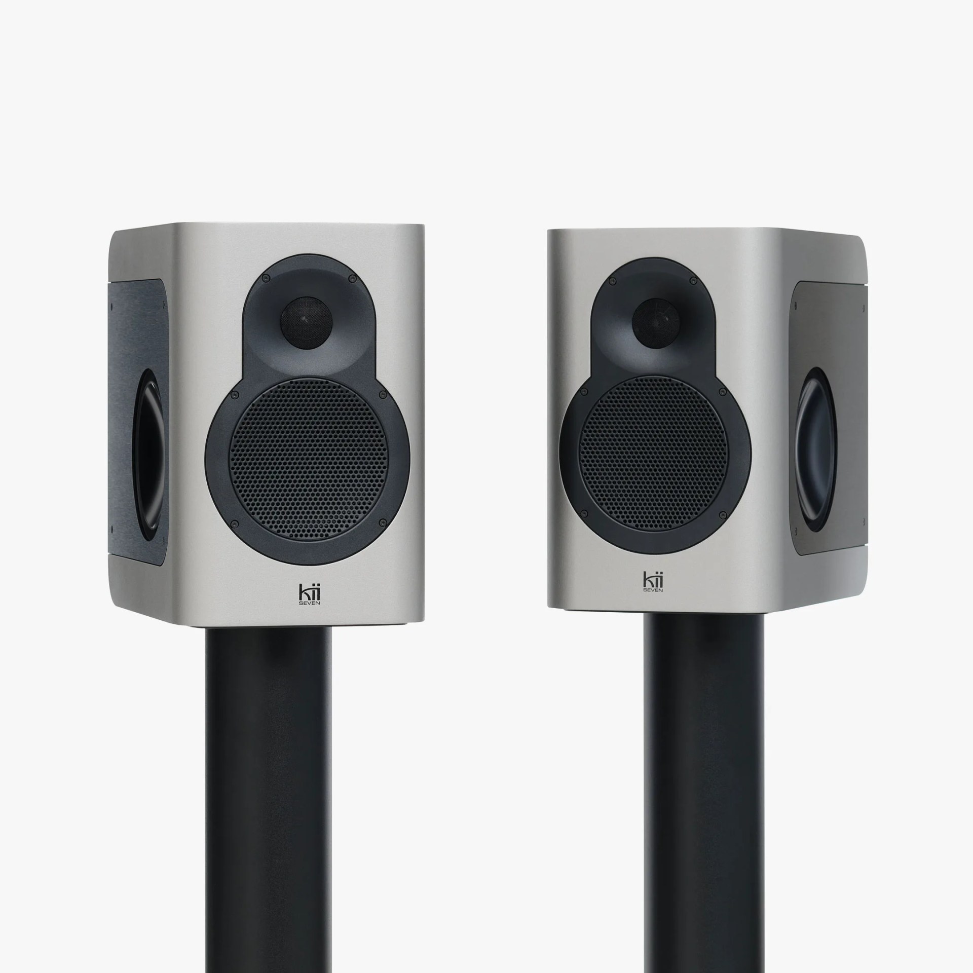 Pair of silver Kii Seven speakers with black speaker stands and side bass radiators.