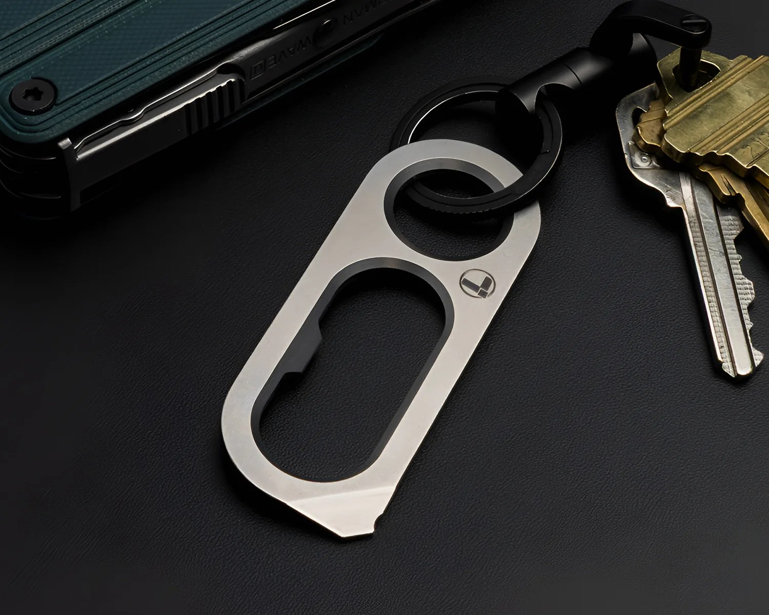Silver metal keychain multitool with a bottle opener and pry bar attached to a black keyring with keys.