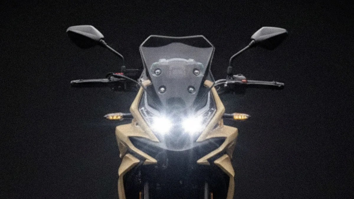 Front view of a beige motorcycle with dual headlights turned on and black rearview mirrors against a dark background.