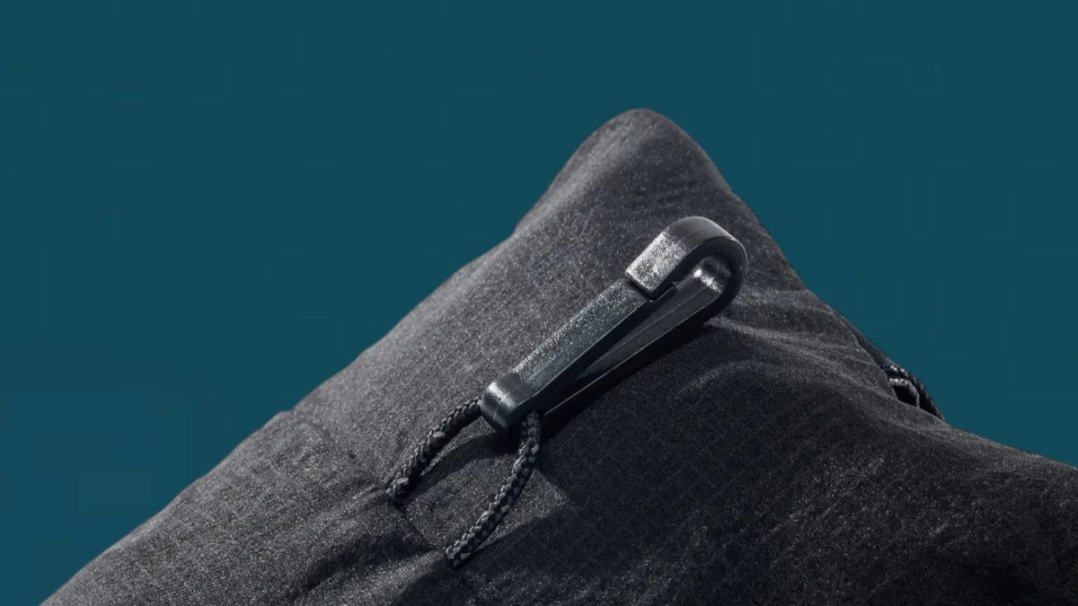 Close-up of a black fabric with a black plastic clip attached to a braided cord loop.