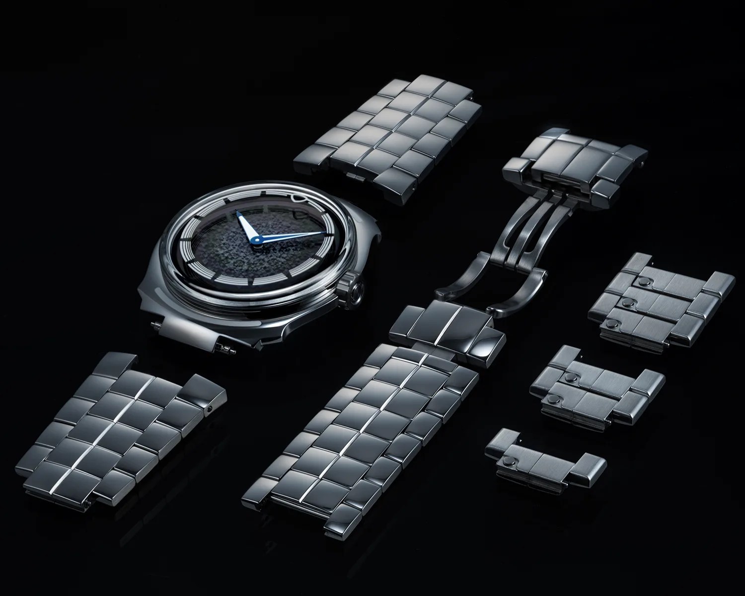 Disassembled stainless steel watch with a textured black dial and blue hands on a black surface.