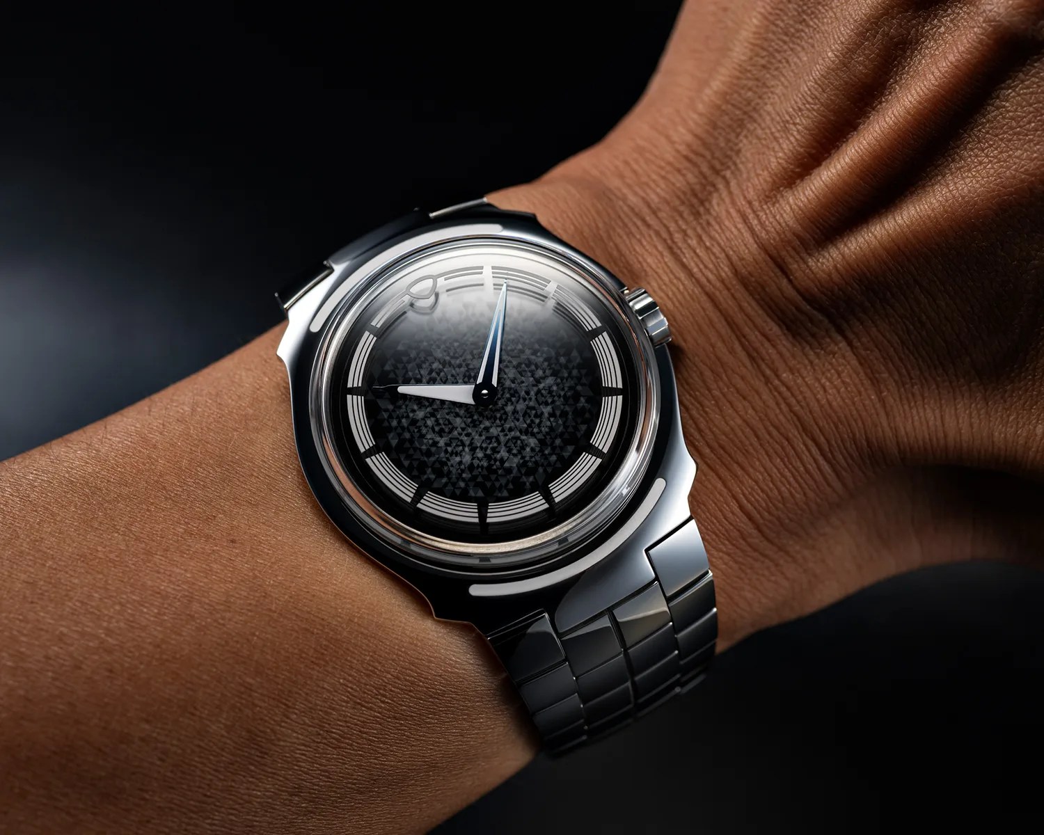 Polished silver wristwatch with a black patterned dial and silver bracelet worn on a wrist.