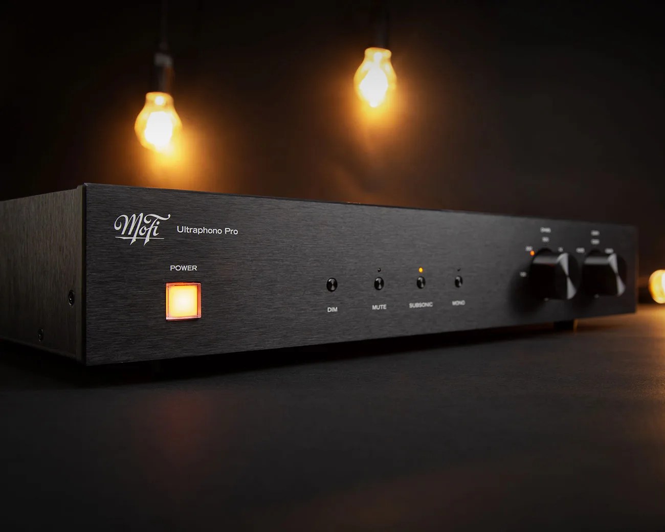 Black MoFi Ultraphono Pro audio preamplifier with illuminated power button and control knobs on a dark surface.