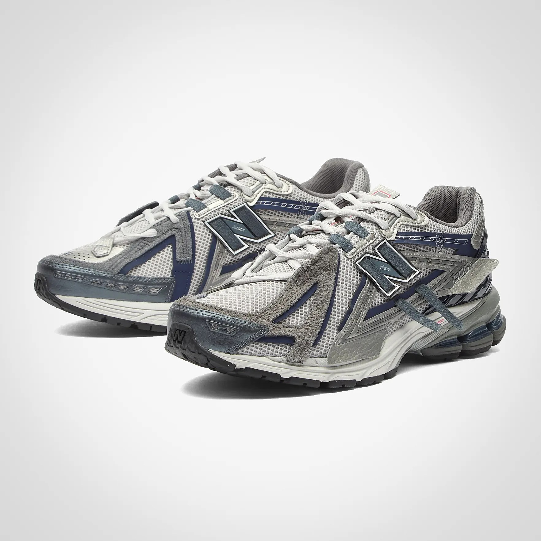 Pair of gray and navy New Balance running shoes with mesh and suede upper and cushioned sole.