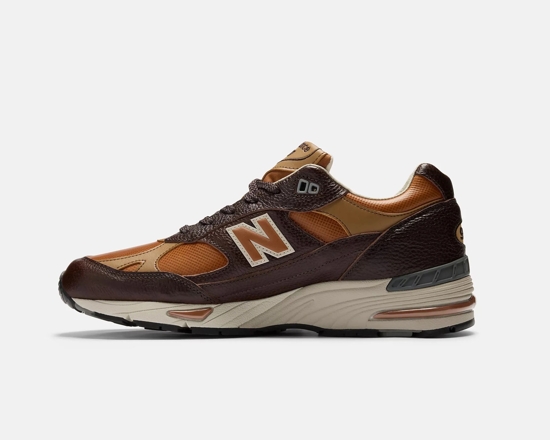 Brown and tan New Balance sneaker with textured leather and mesh upper, beige midsole, and black outsole.