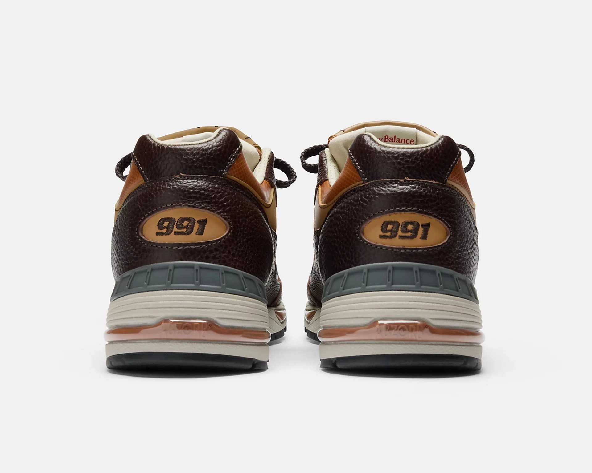 Pair of brown and tan New Balance 991 sneakers shown from the back with gray and beige midsoles.