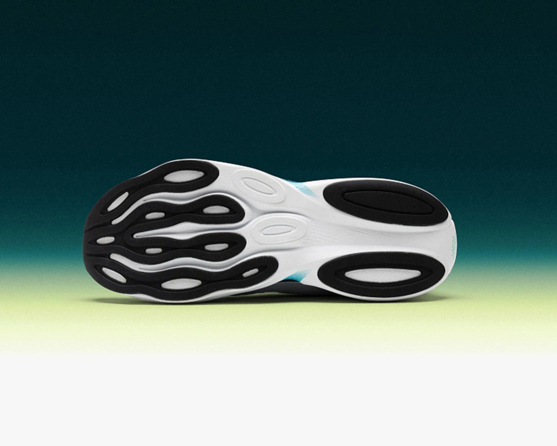 White and black rubber shoe sole with oval-shaped tread patterns on a gradient green background.