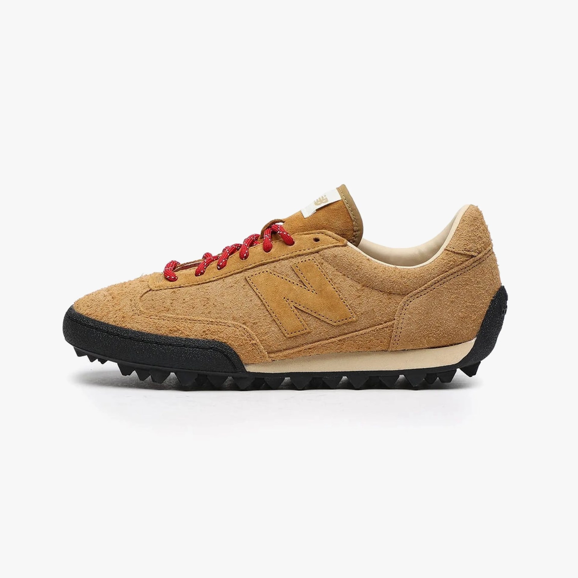 Tan suede New Balance sneaker with red laces and black textured sole.