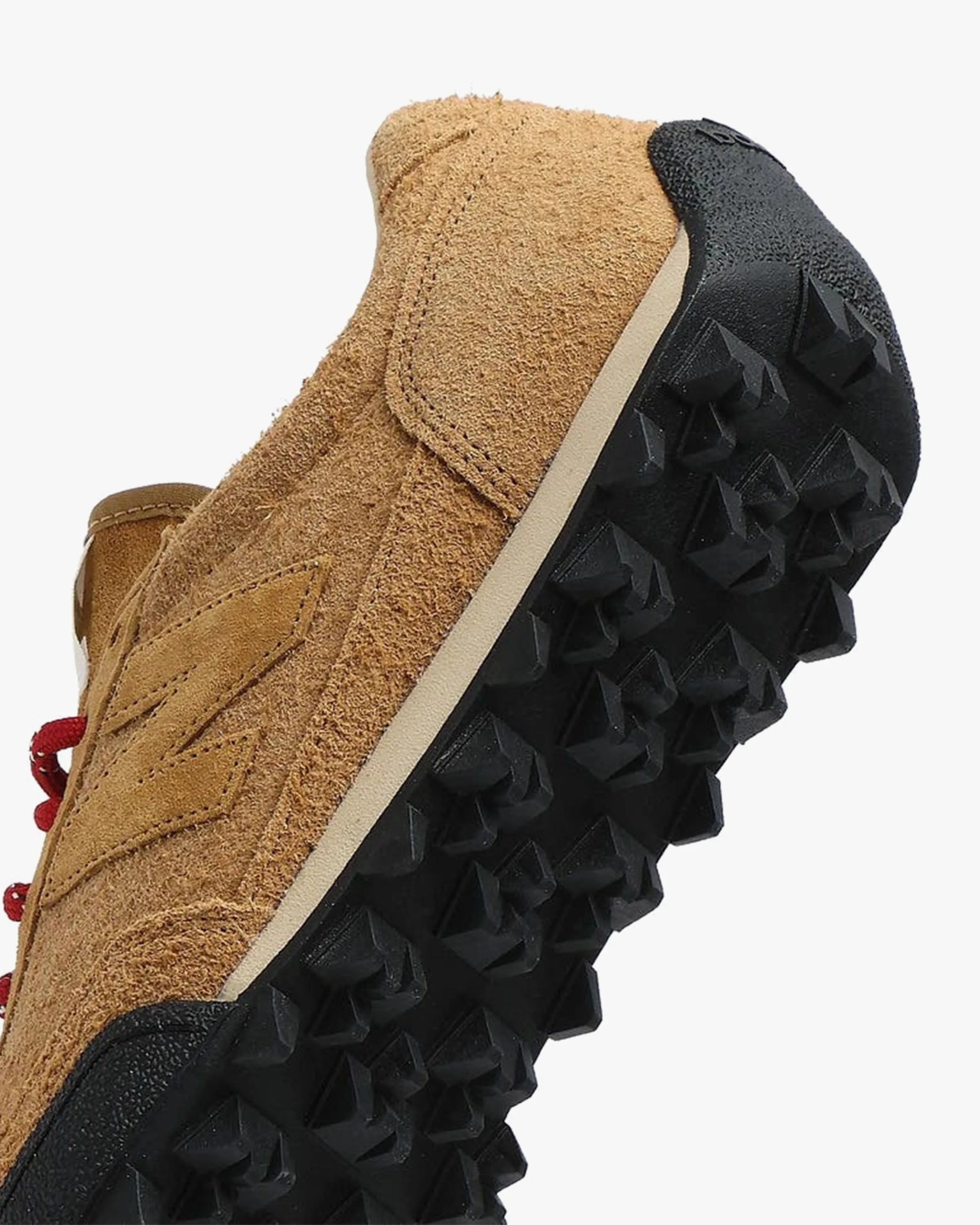 Brown suede sneaker with black studded rubber sole and red laces.