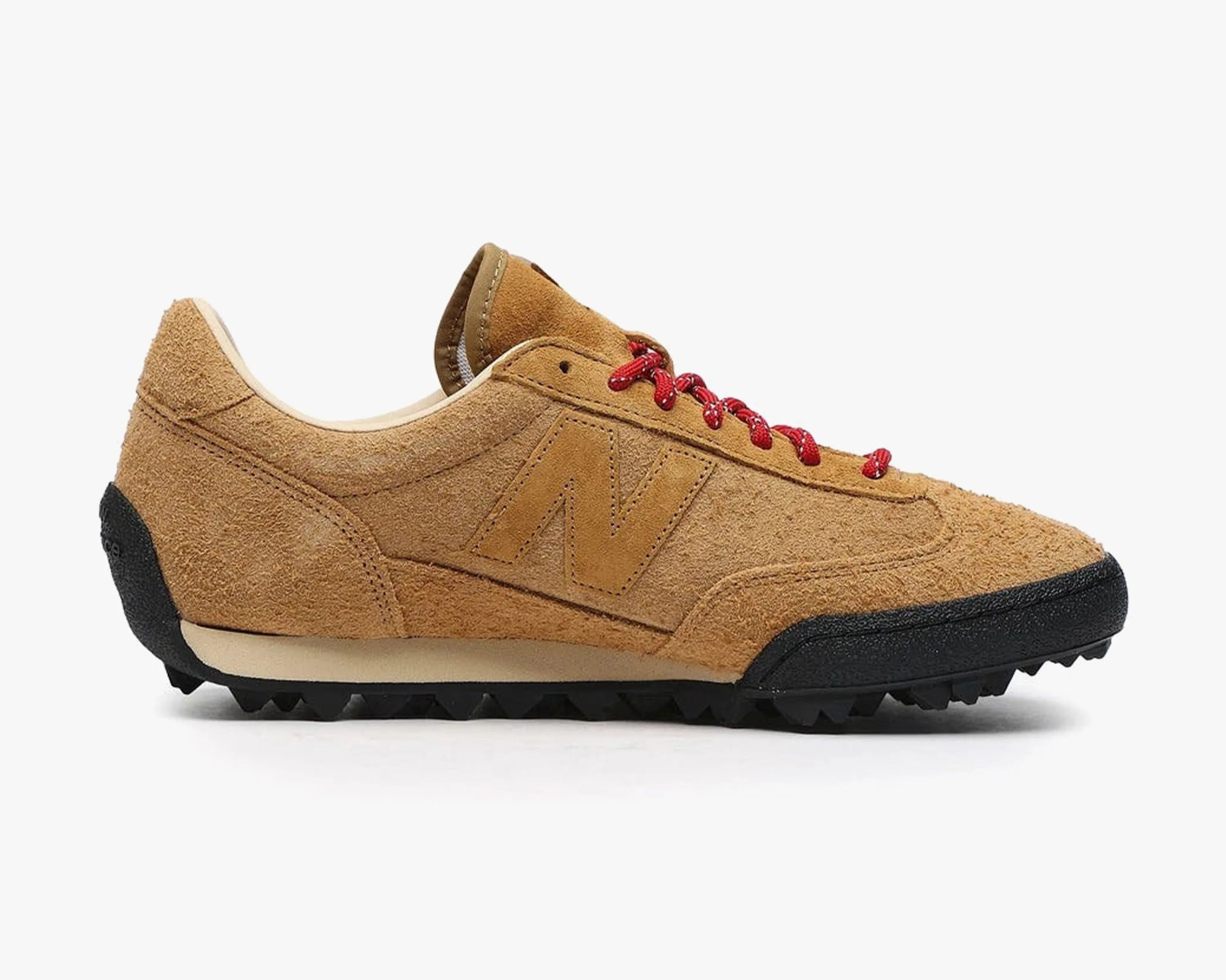 Tan suede New Balance sneaker with red laces and black textured sole.