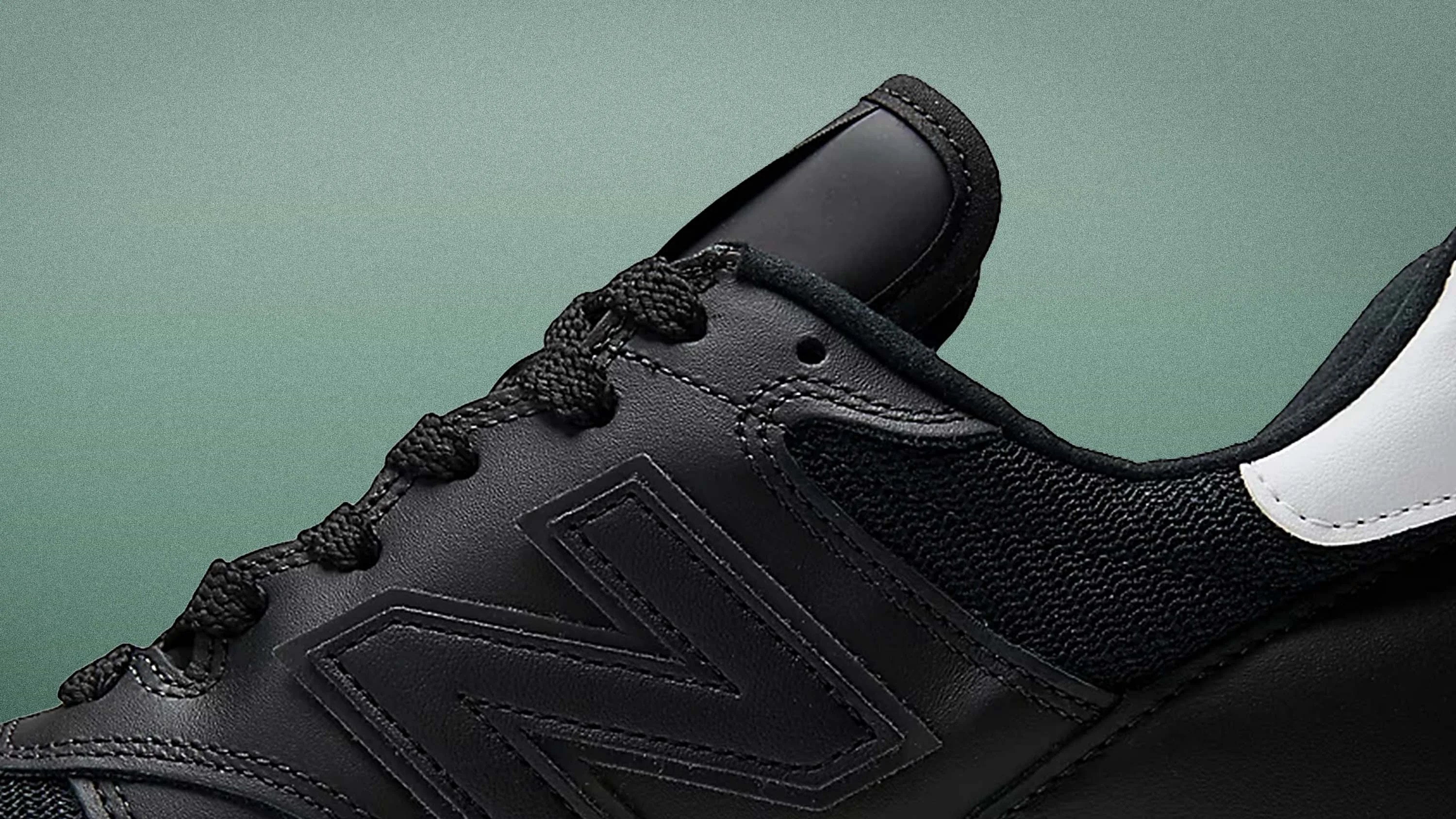 Close-up of a black New Balance sneaker with textured fabric and leather panels and black laces.