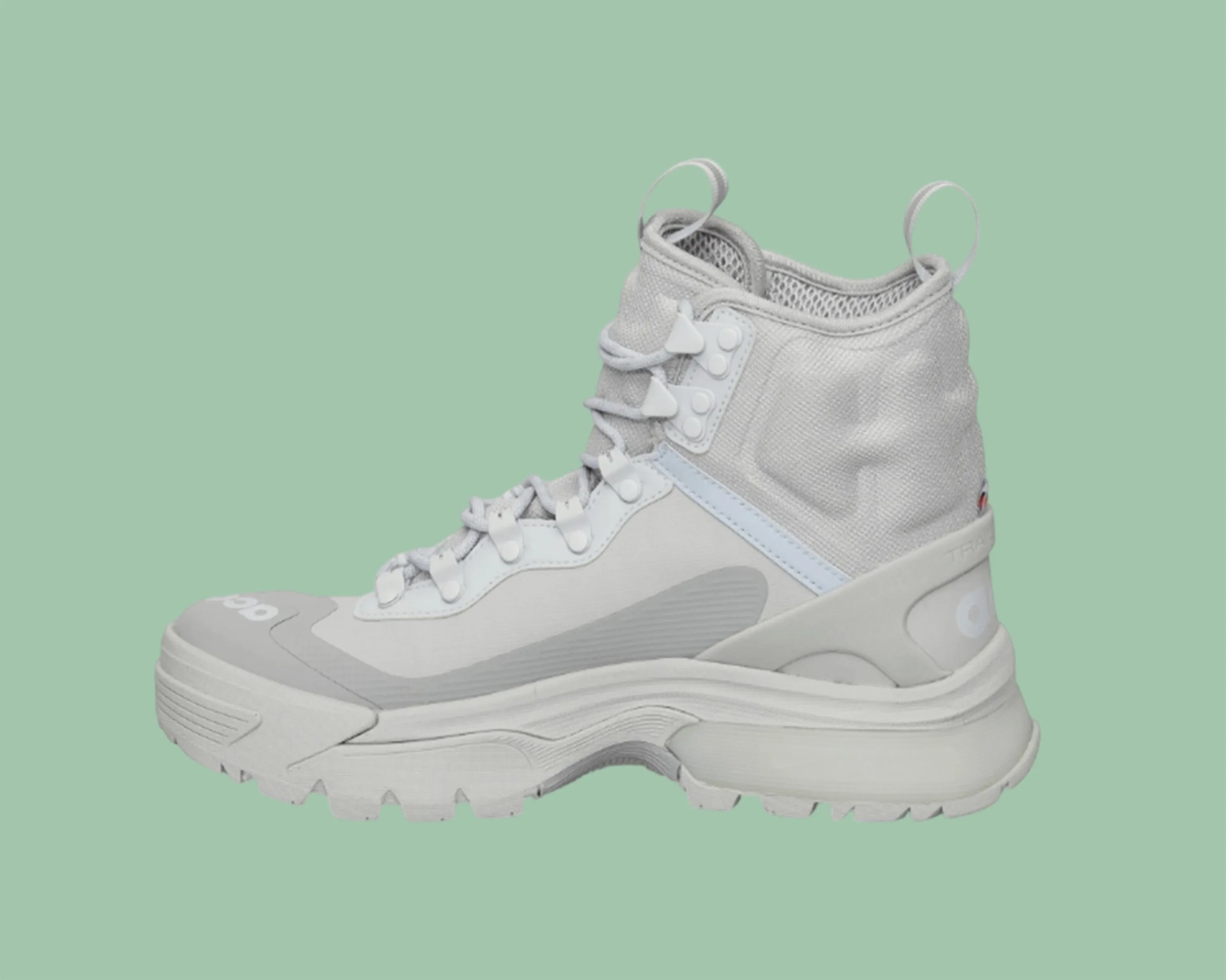 Light gray high-top hiking boot with thick sole and lace-up front on a green background.
