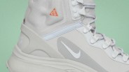 Close-up of a light gray Nike ACG hiking boot with white laces and an orange ACG logo on the side.