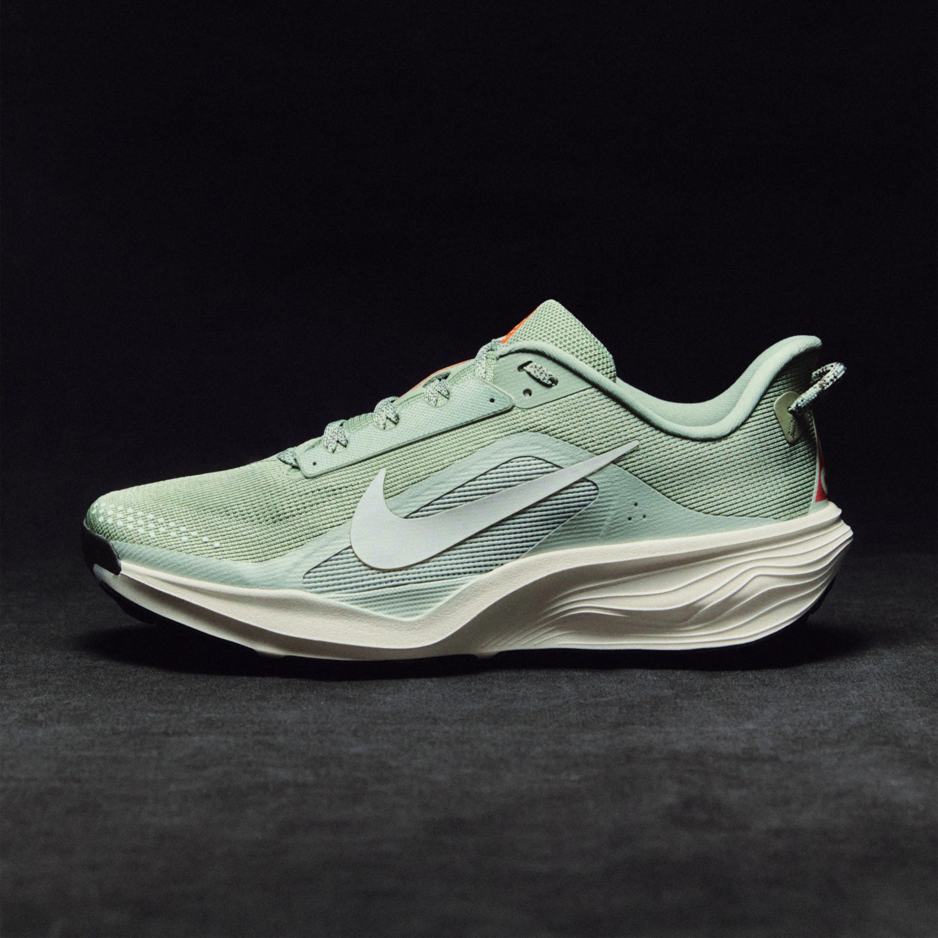 Light green Nike running shoe with white swoosh logo and thick white sole on dark background.