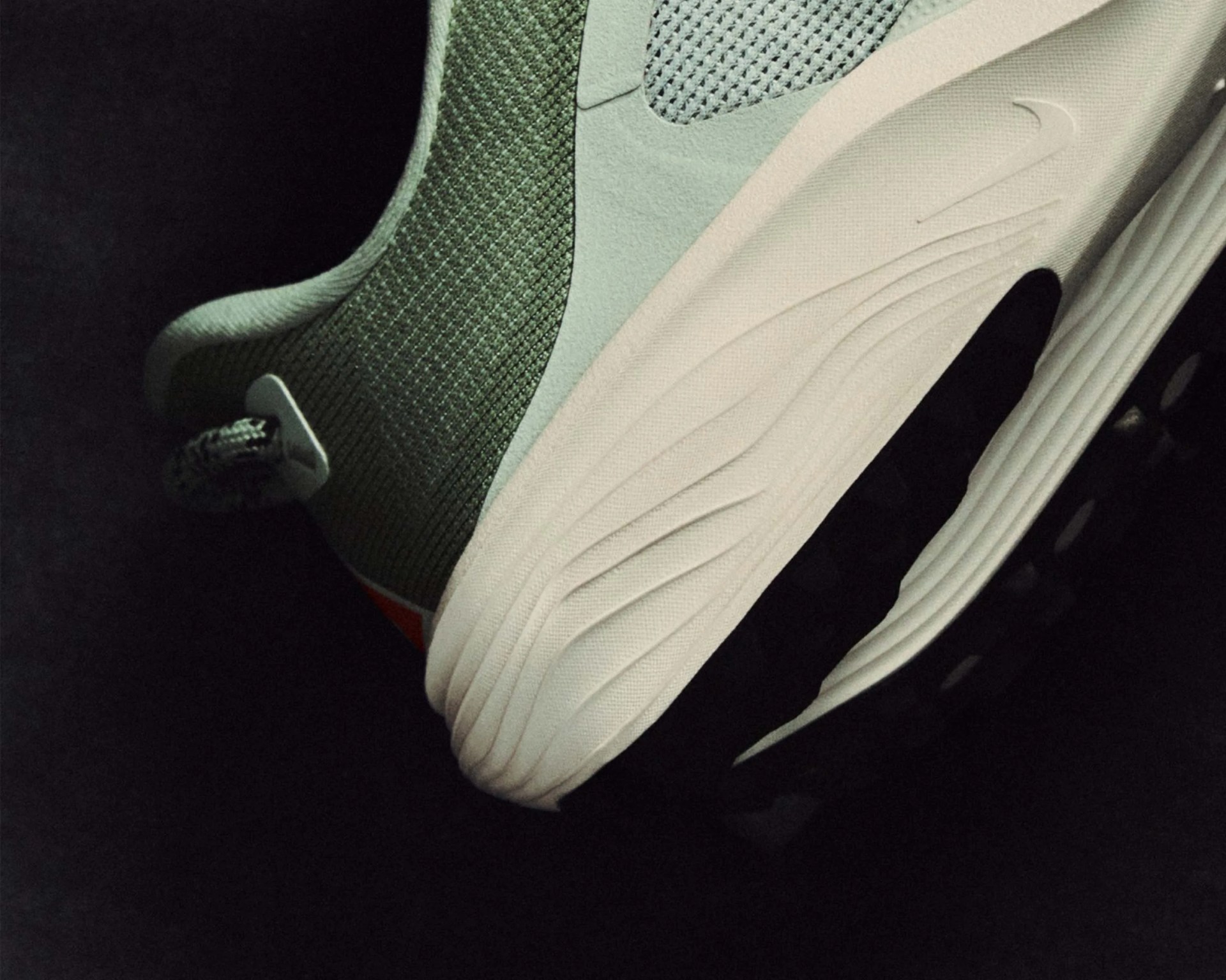 Close-up of the heel and midsole of a green and white Nike sneaker with textured fabric and a black outsole.