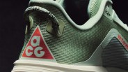 Close-up of a green textured sneaker heel with a red triangular ACG logo and white sole.