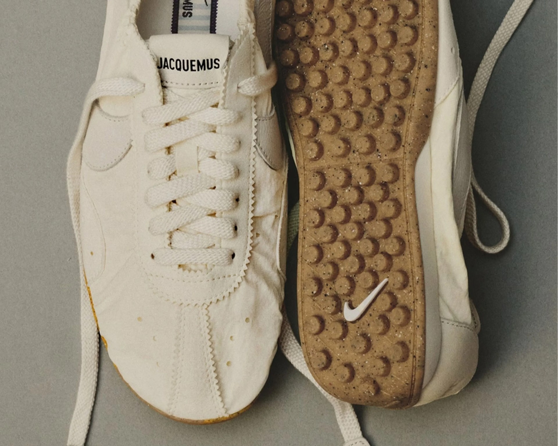 Pair of off-white Jacquemus sneakers with textured brown soles featuring a white Nike swoosh logo.