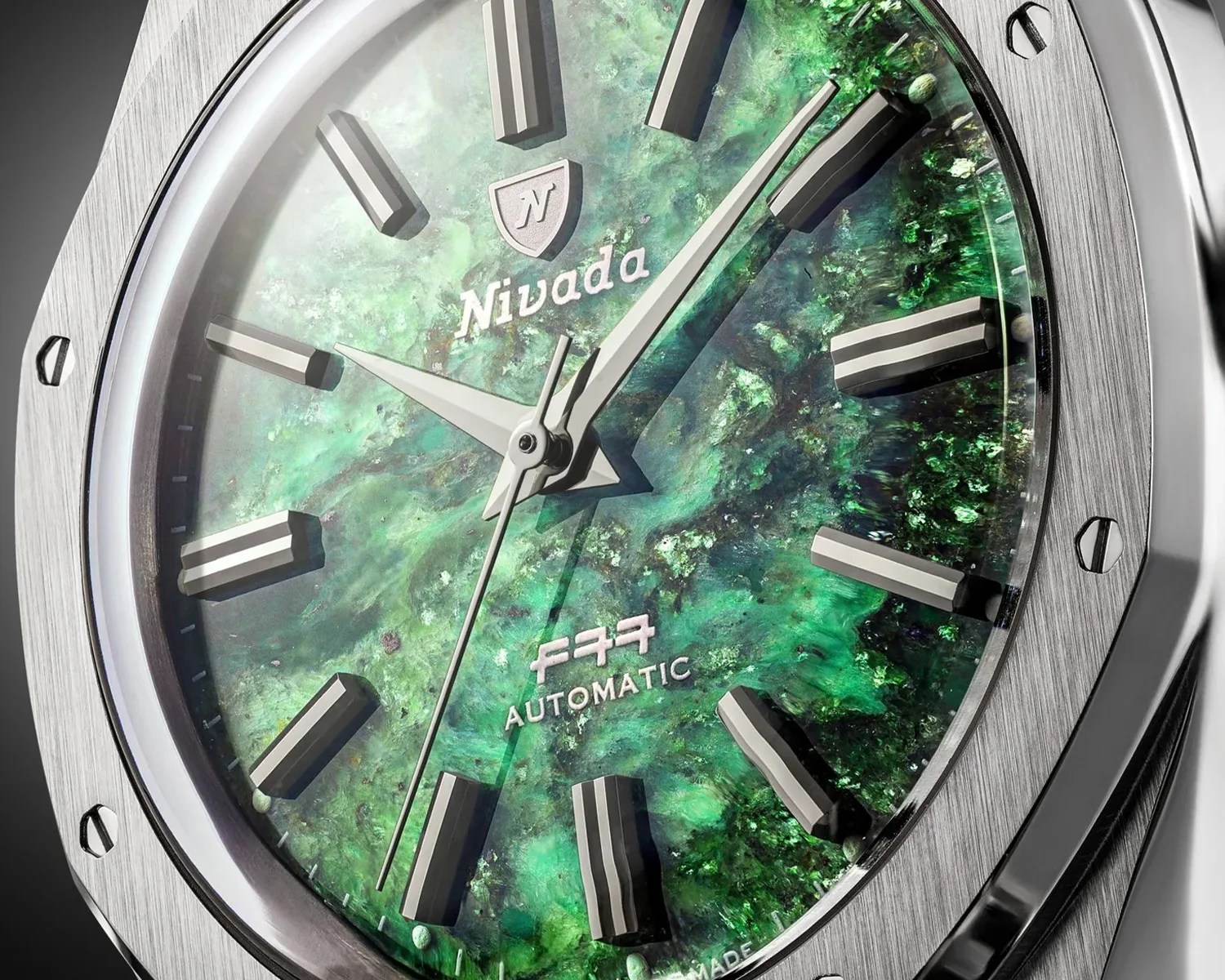 Close-up of a Nivada wristwatch with a green marbled dial, silver hour markers, and a brushed stainless steel bezel.