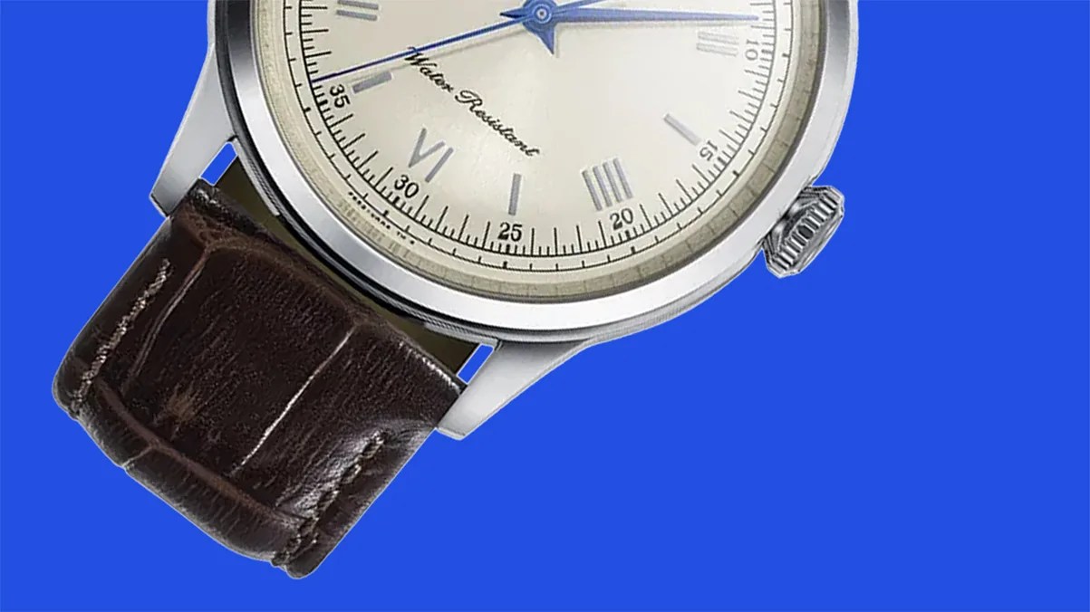 Silver watch with a cream dial, blue hands, Roman numerals, and a dark brown leather strap on a blue background.