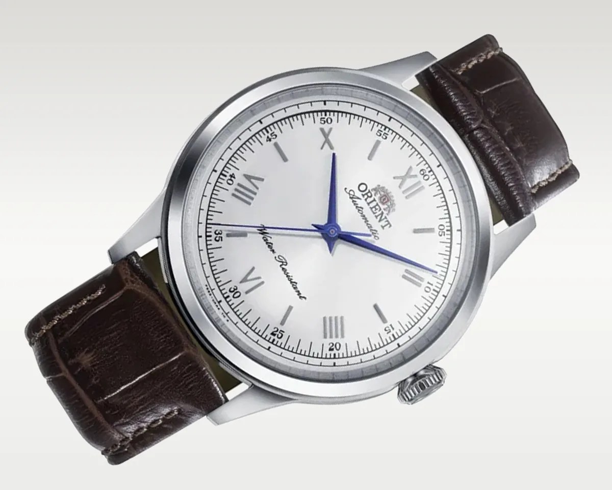 Silver round watch with white dial, blue hands, Roman numerals, and dark brown leather strap.