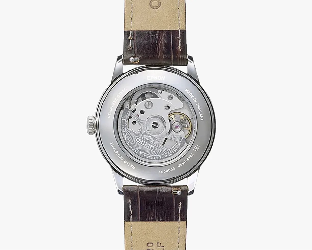 Back view of a stainless steel Orient watch with visible mechanical movement and brown leather strap.