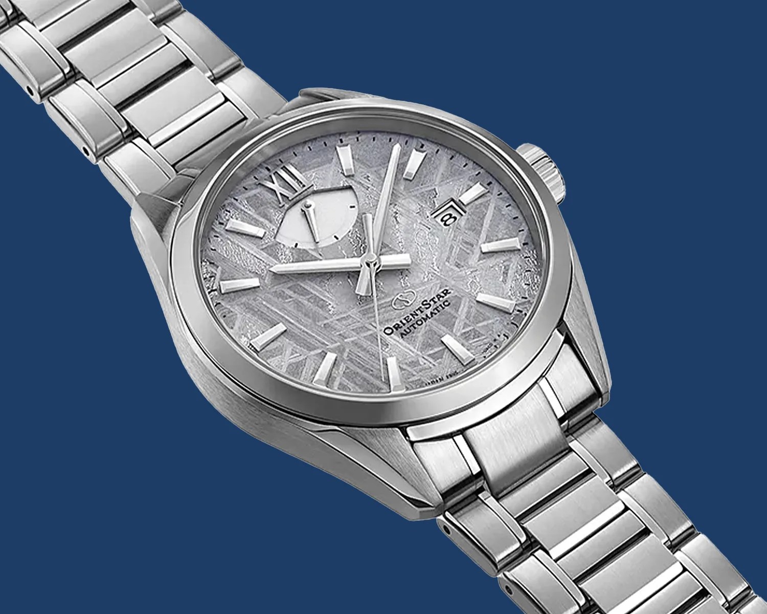 Silver stainless steel Orient Star automatic wristwatch with textured gray dial and date window.