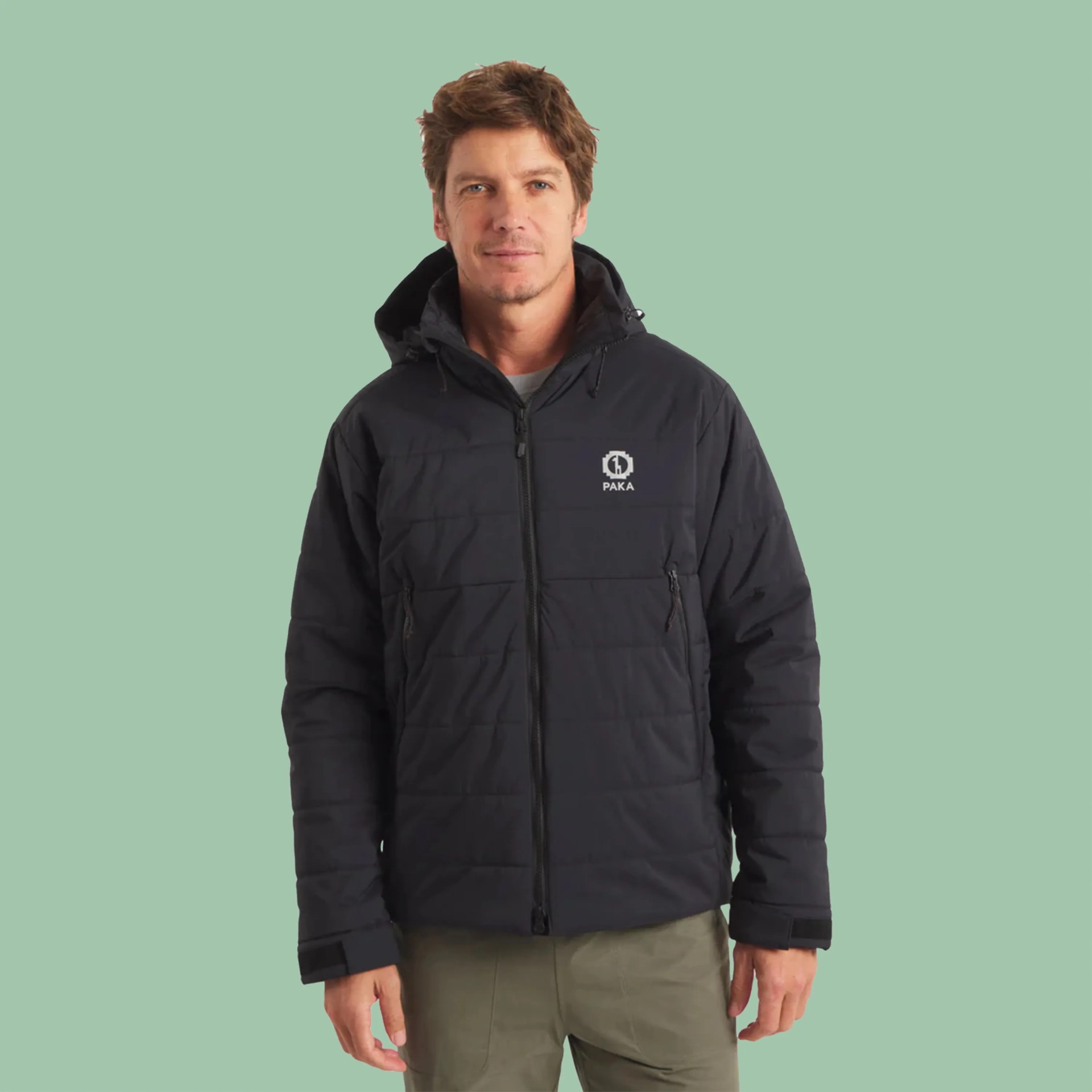 Black hooded puffer jacket with front zipper and PAKA logo worn by a person.