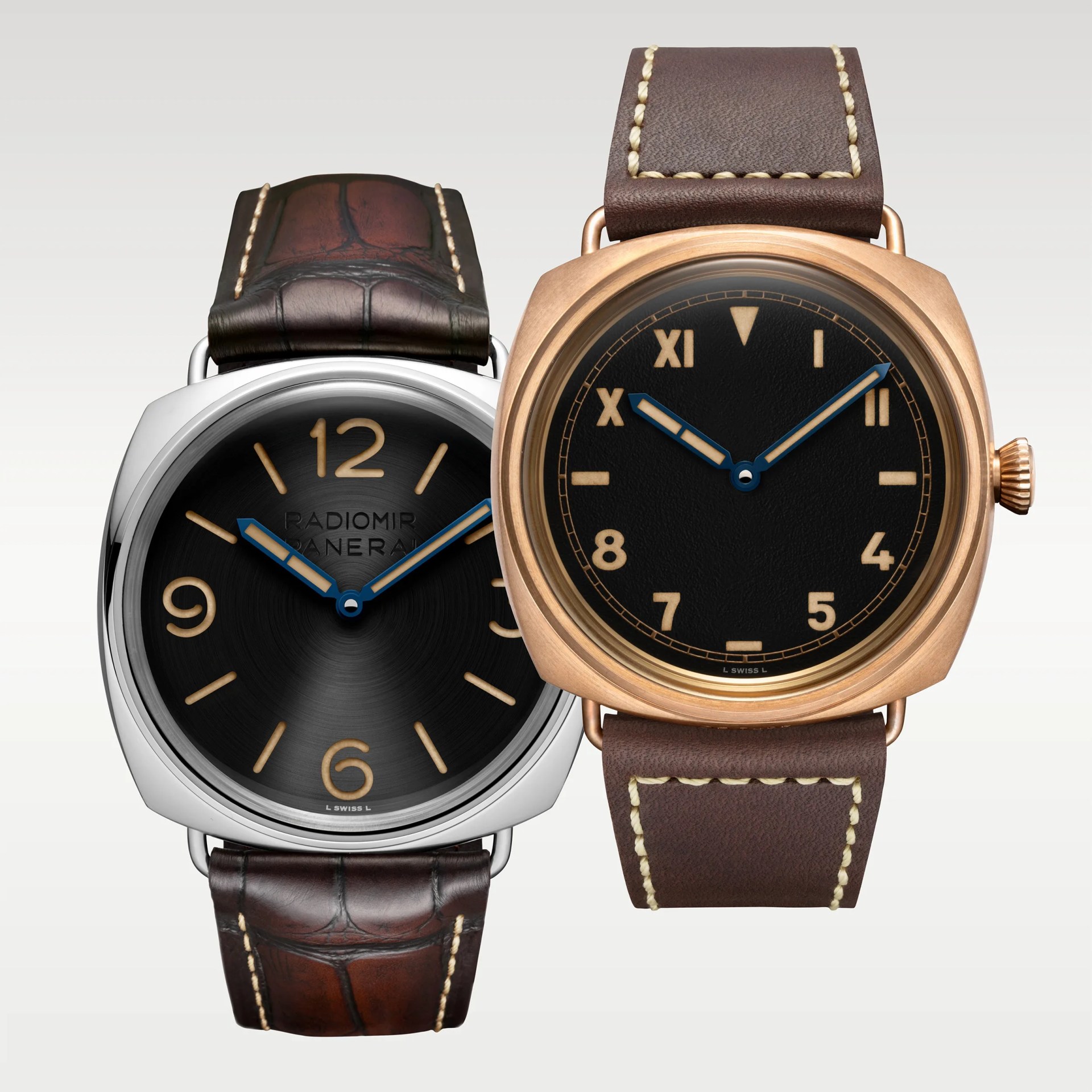 Two wristwatches with black dials, blue hands, and brown leather straps, one with a silver case and Arabic numerals, the other with a bronze case and mixed Roman and Arabic numerals.