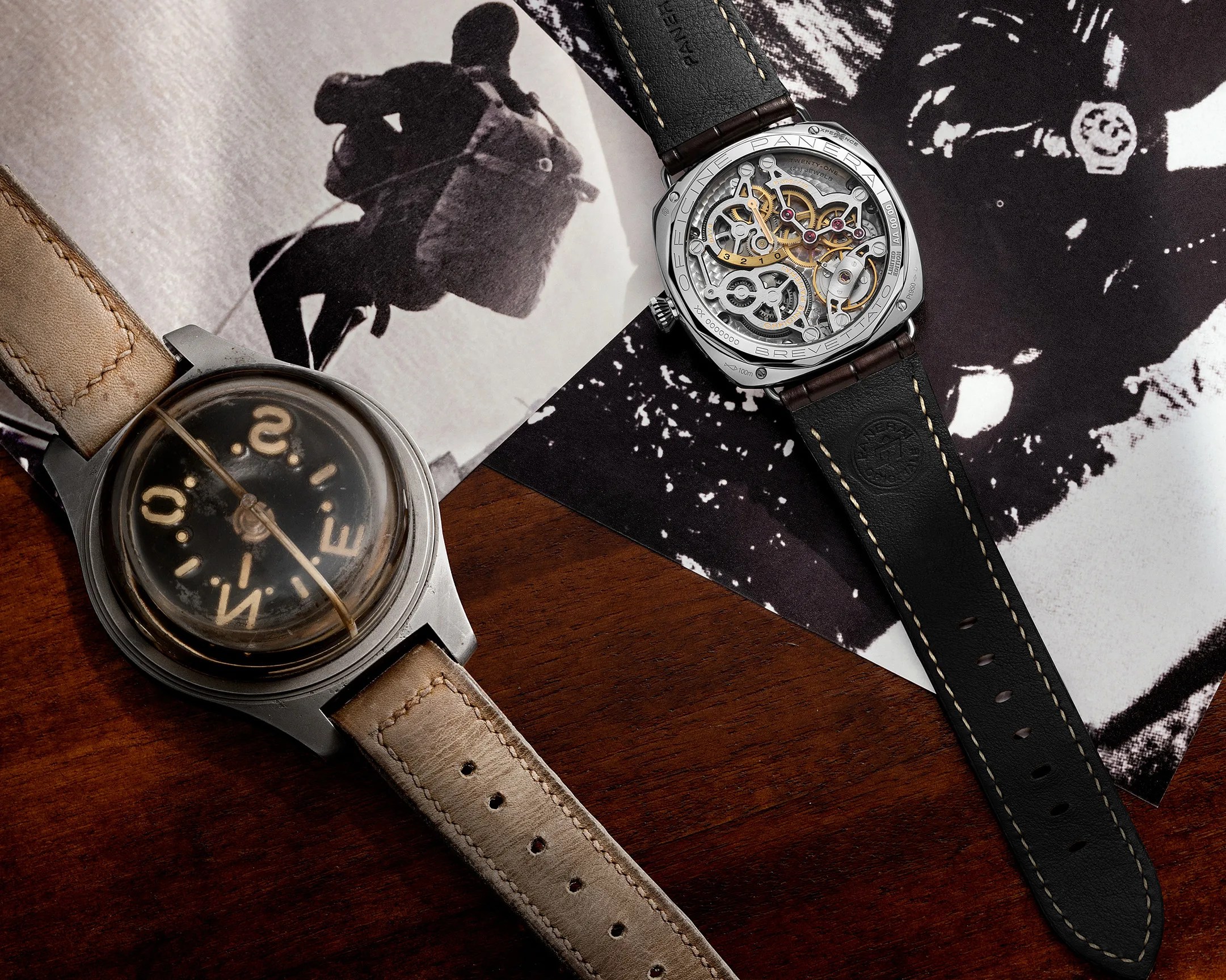 Two wristwatches on a wooden surface, one with a beige leather strap and domed compass dial, the other with a black leather strap and visible mechanical movement.