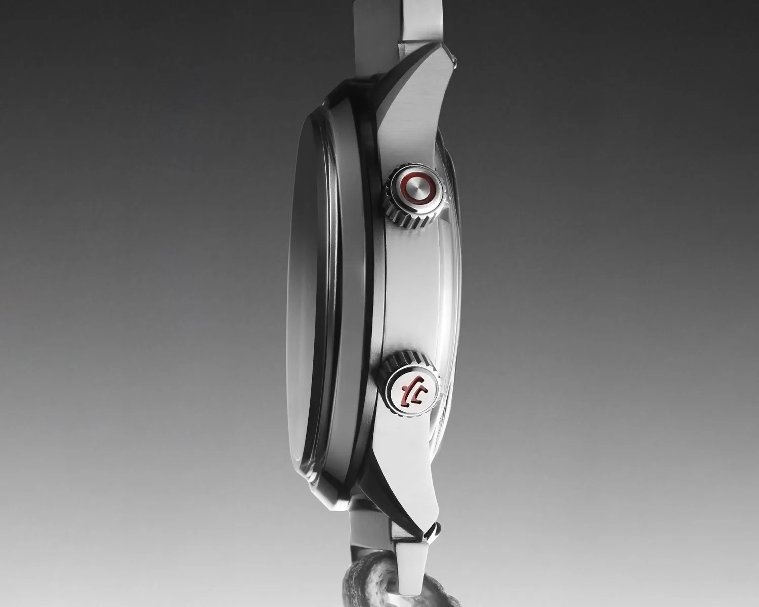 Side view of a silver watch case with two textured crowns, one featuring a red circle and the other a red logo.