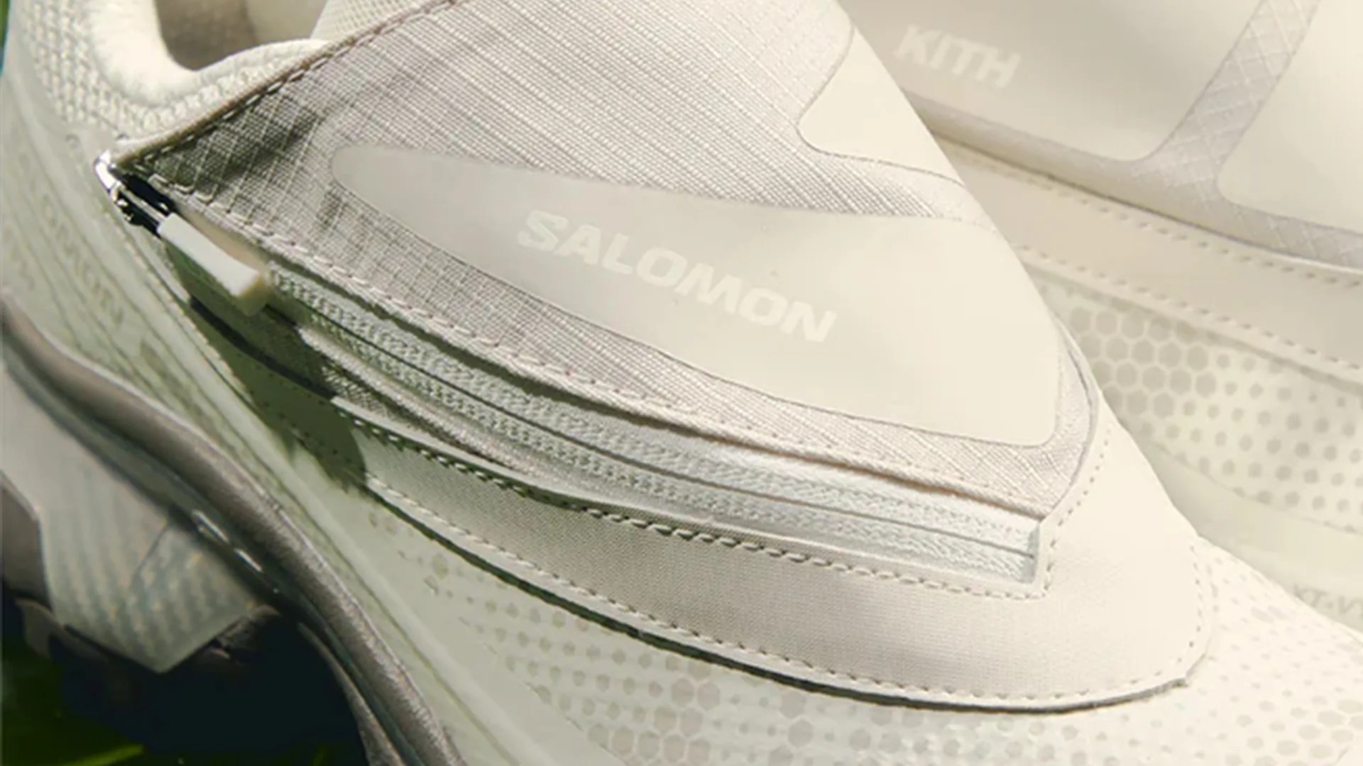 Close-up of a white Salomon sneaker with a zippered panel and textured fabric.