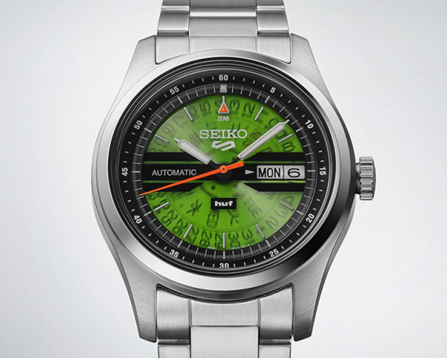 Seiko automatic wristwatch with green dial, orange second hand, day-date display, and stainless steel bracelet.