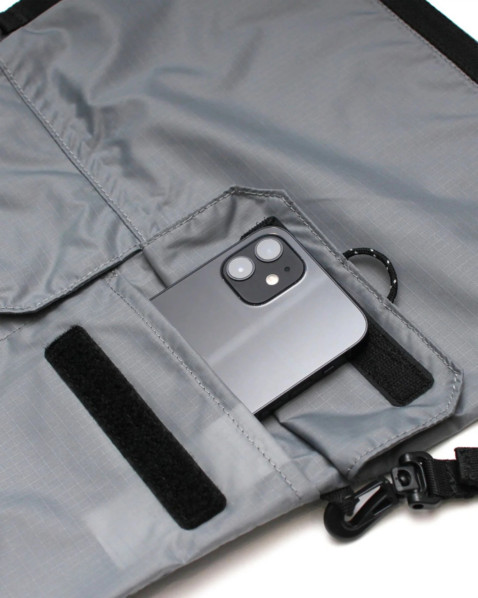 Gray ripstop fabric pouch with black hook-and-loop fasteners and a black smartphone partially inside.