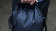 Black waterproof bag with adjustable strap held in a hand.