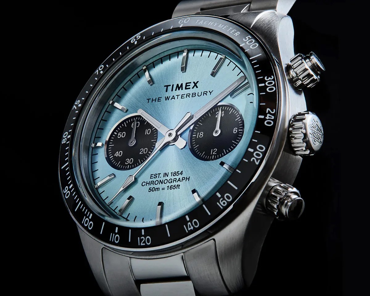 Close-up of a Timex Waterbury chronograph watch with a light blue dial, black subdials, and stainless steel case and bracelet.