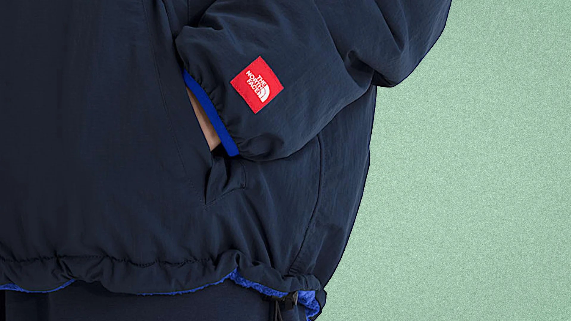 Close-up of a navy blue The North Face jacket sleeve with a red logo patch and elastic cuff.