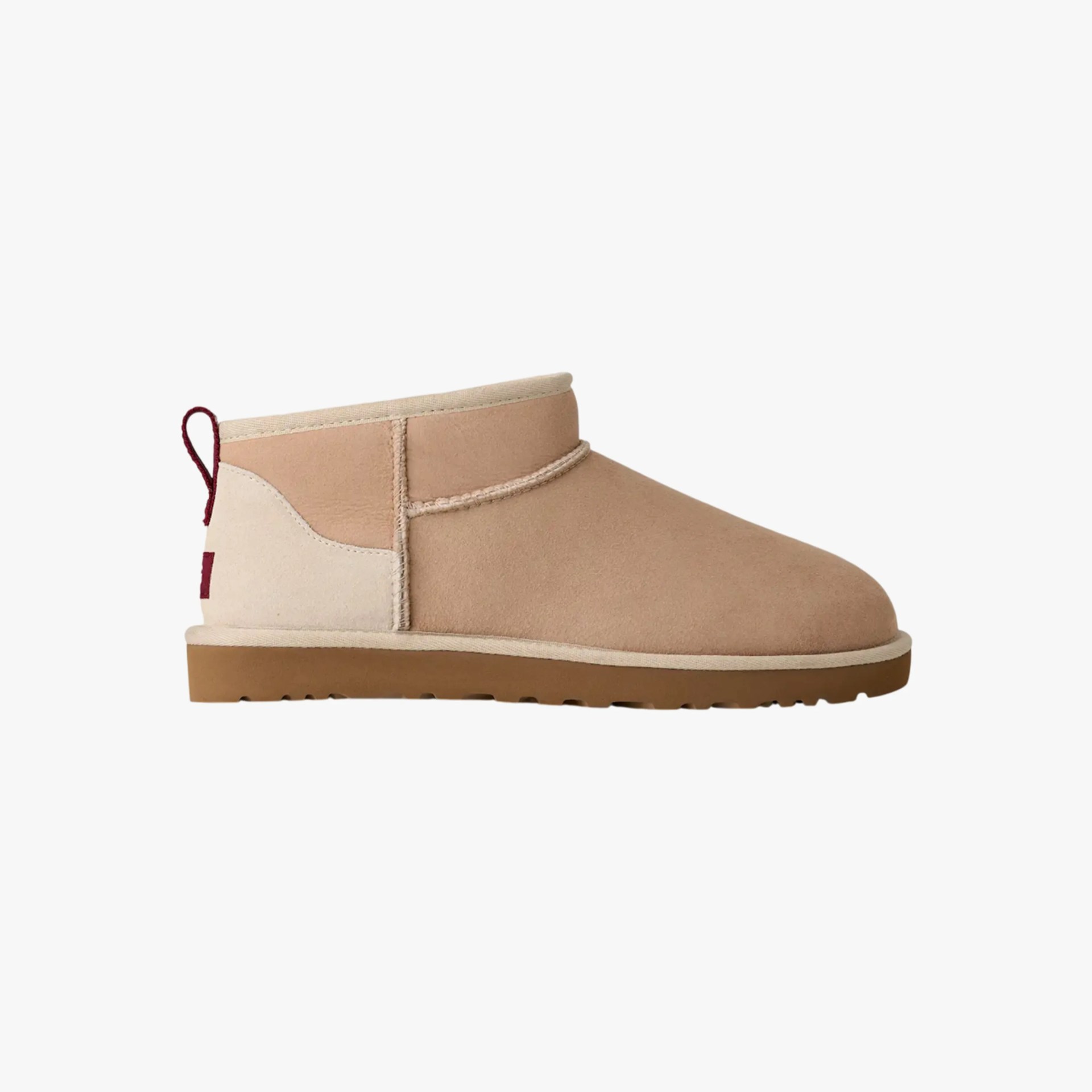 Tan suede ankle boot with beige trim, brown sole, and red pull tab at the heel.