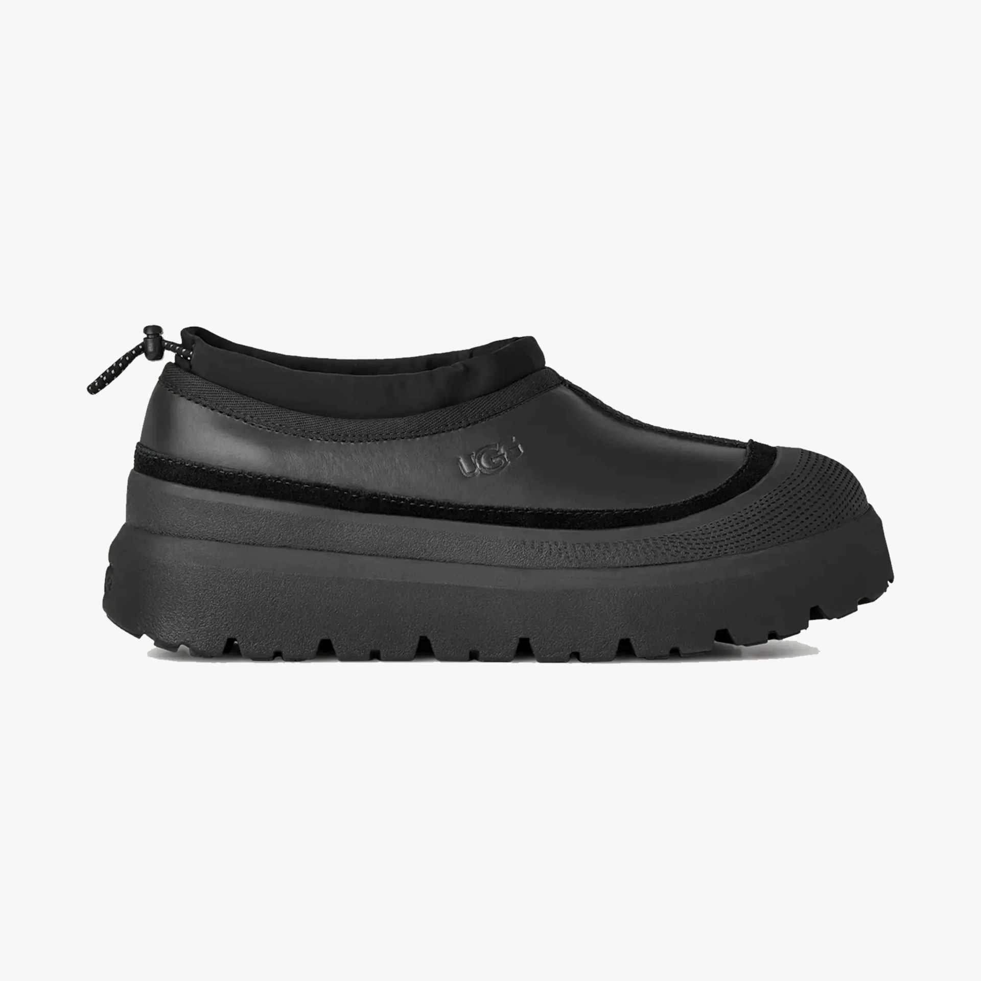 Black slip-on shoe with thick textured sole and UGG logo on the side.