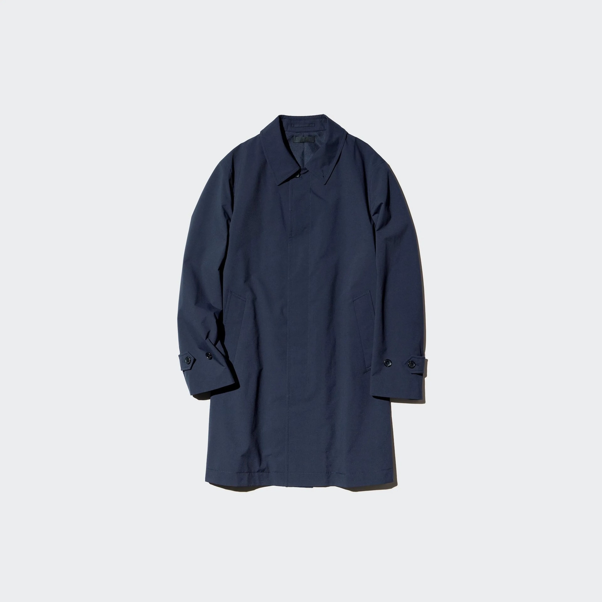 Navy blue long coat with buttoned cuffs and side pockets laid flat on a light background.