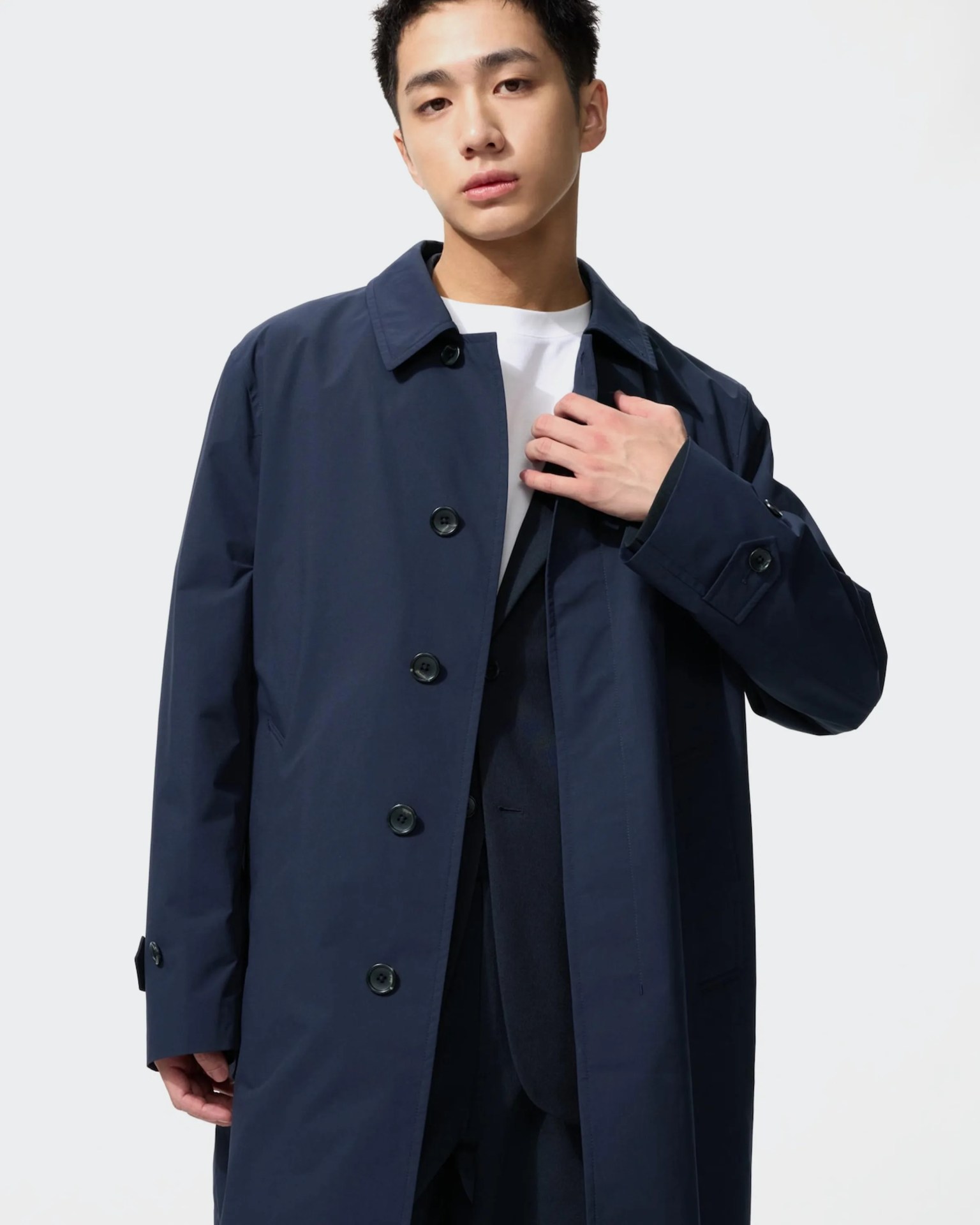 Navy blue buttoned trench coat worn over a dark suit and white shirt.