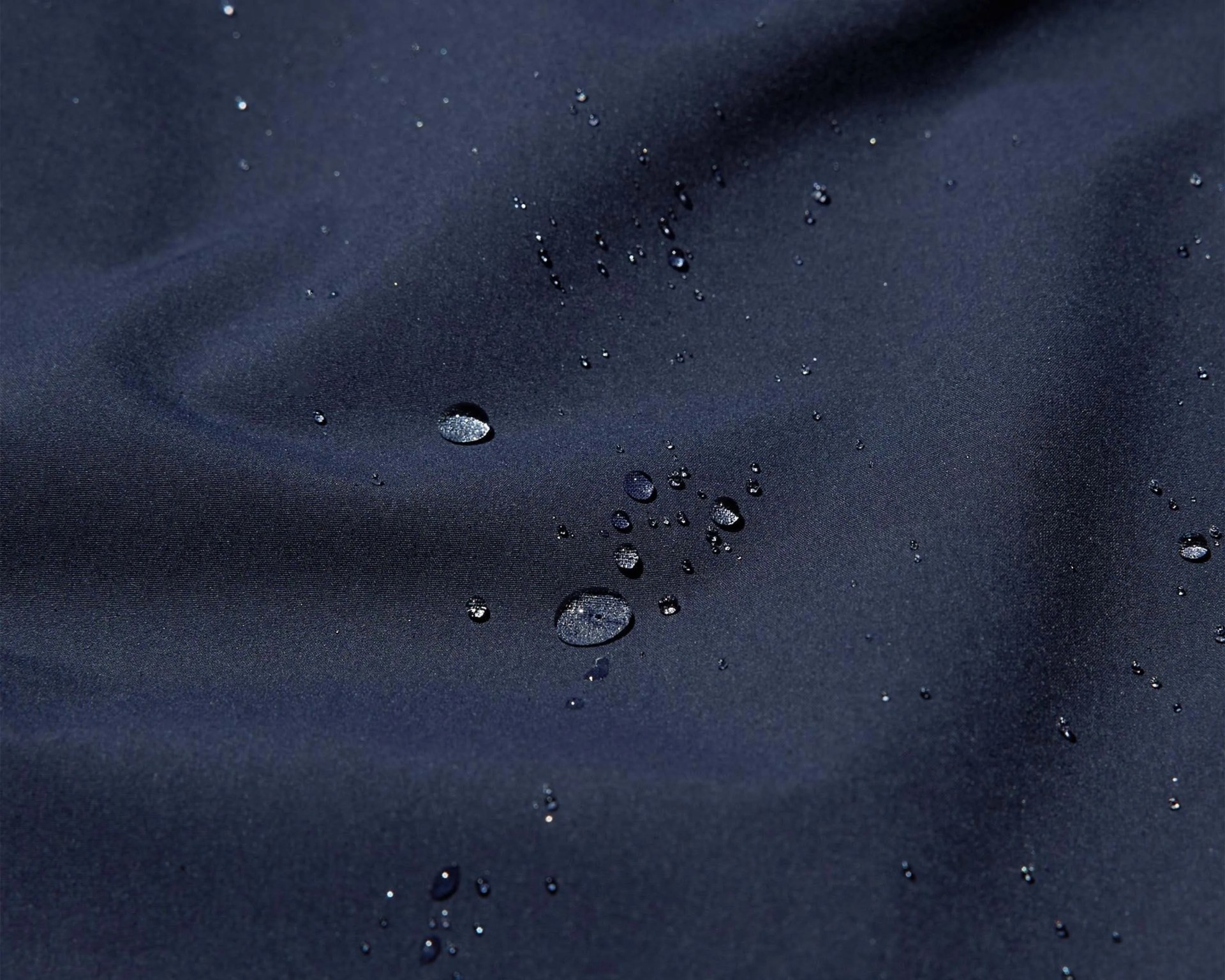 Water droplets beading on dark navy waterproof fabric.