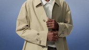 Beige trench coat with buttoned cuffs worn over a light-colored collared shirt.