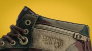 Close-up of a camouflage fabric shoe with brown laces, metal eyelets, and a suede patch with "HALF CAB" embossed next to a zipper.