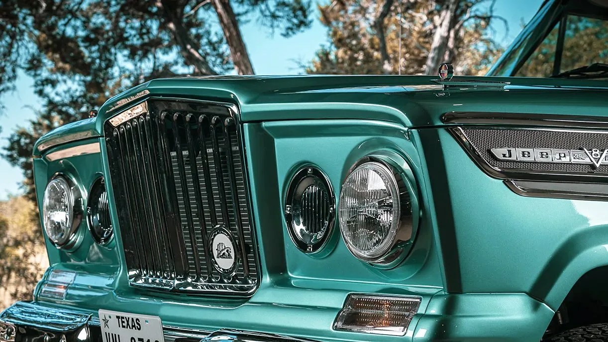 Front grille and headlights of a teal vintage Jeep Wagoneer with a Texas license plate.