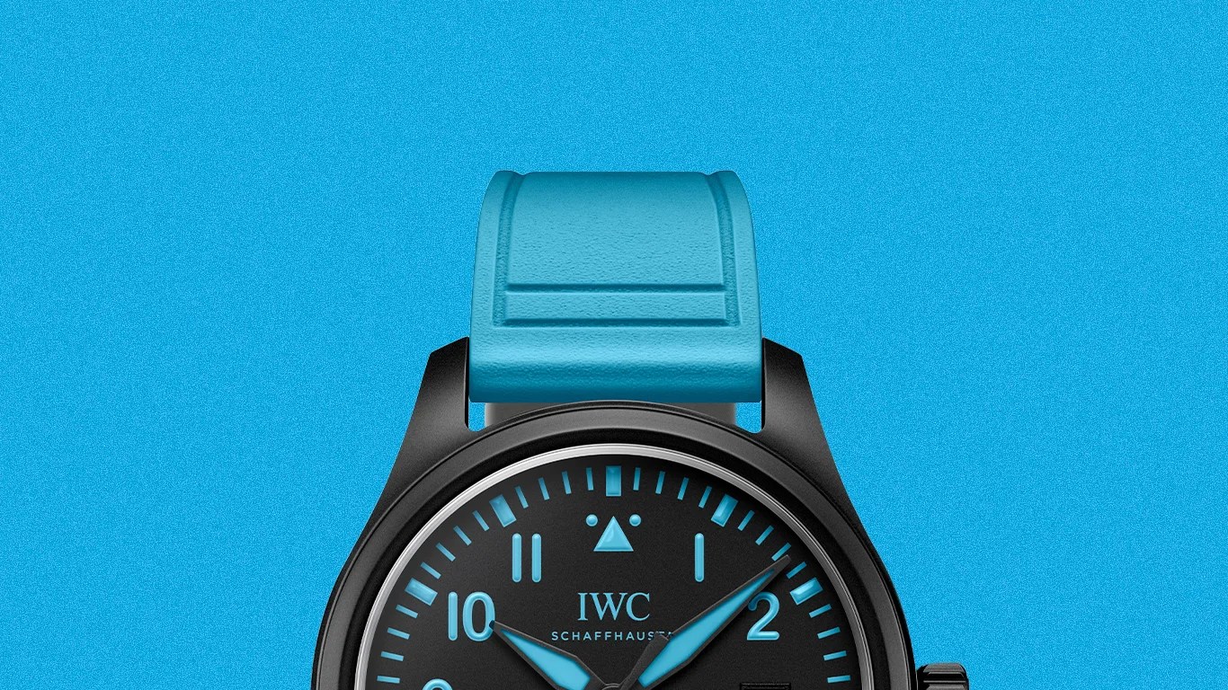 Black IWC Schaffhausen watch with blue hour markers and hands, and a blue rubber strap on a blue background.