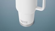 White YETI insulated mug with a handle on a blue surface.
